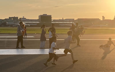 朝焼けの滑走路で、大阪国際空港のランウェイウォークに参加した子どもたちが走ったり歩いたりして非日常の体験を楽しむ様子。