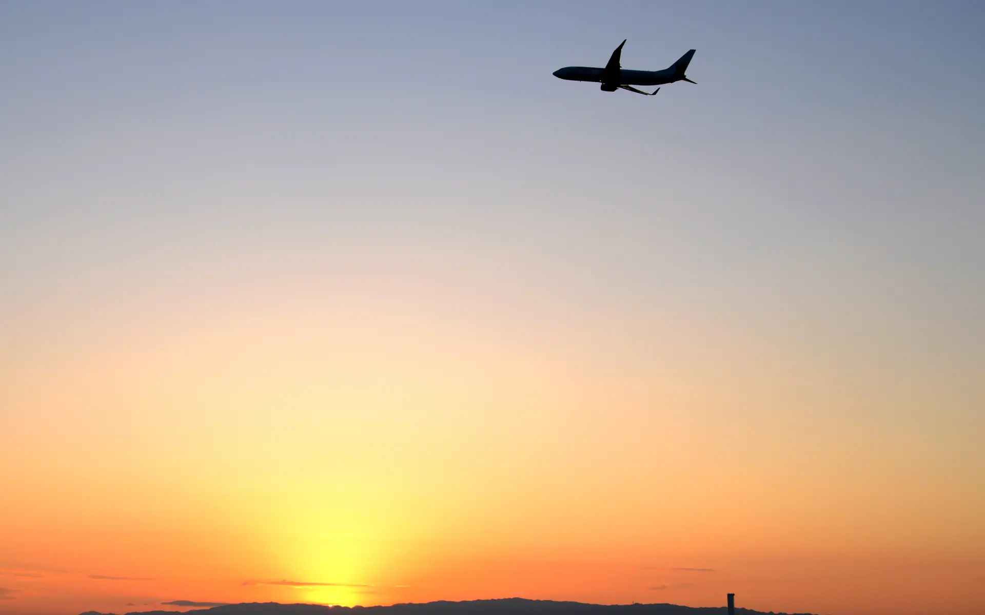 An airplane flying across the sunrise sky